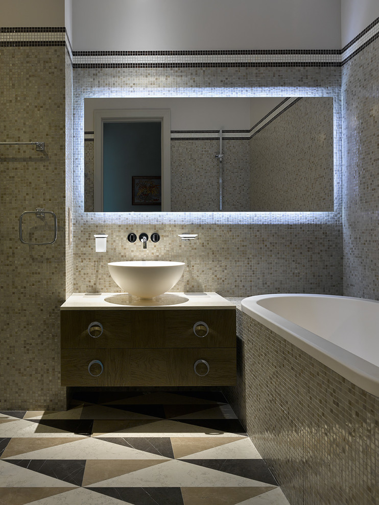 Inredning av ett modernt en-suite badrum, med släta luckor, skåp i mellenmörkt trä, ett platsbyggt badkar, beige kakel, mosaik, ett fristående handfat och marmorgolv