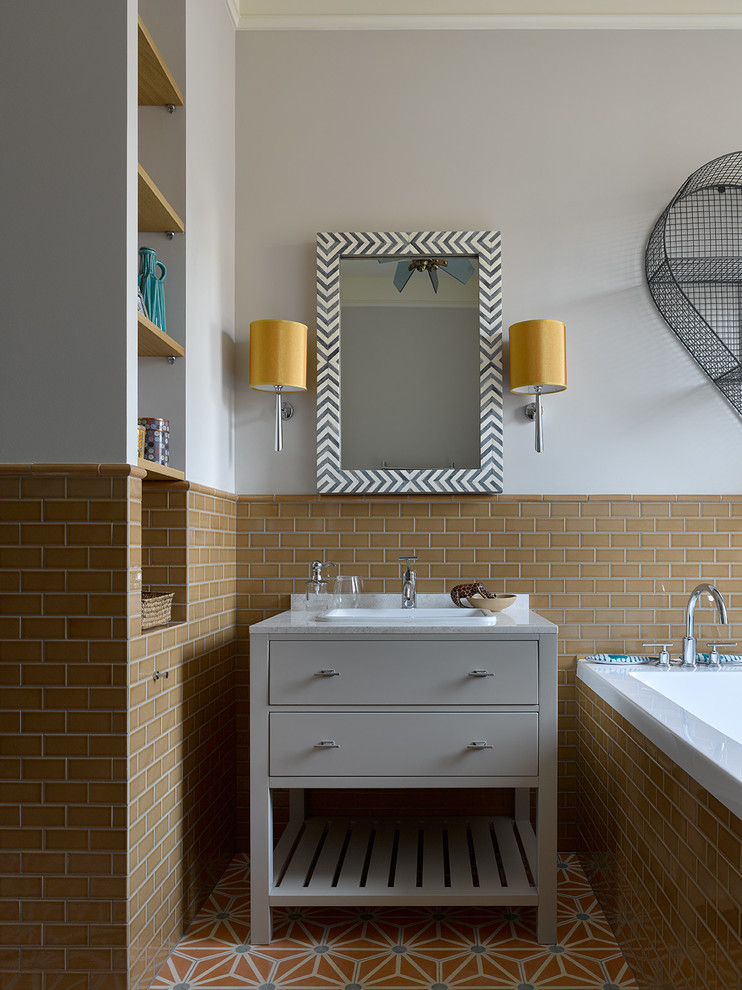 モスクワにあるトランジショナルスタイルのおしゃれな浴室 (フラットパネル扉のキャビネット、グレーのキャビネット、ドロップイン型浴槽、オレンジのタイル、サブウェイタイル、グレーの壁、マルチカラーの床) の写真