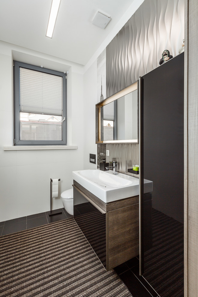 Ejemplo de cuarto de baño contemporáneo pequeño con armarios con paneles lisos, puertas de armario negras, sanitario de pared, suelo de baldosas de cerámica, paredes blancas, lavabo sobreencimera y ventanas