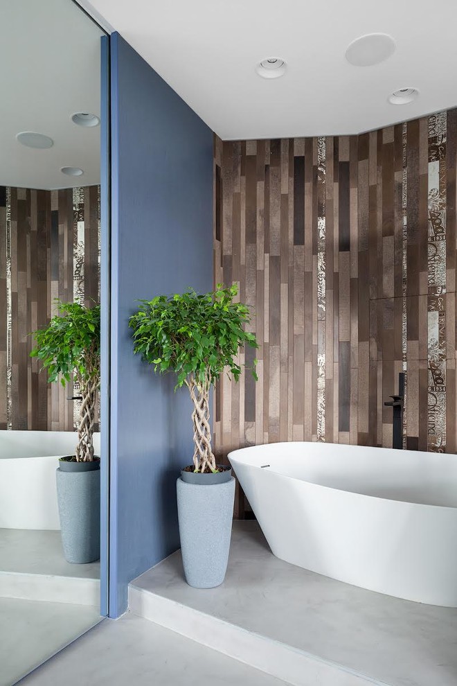 На фото: главная ванная комната: освещение в современном стиле с отдельно стоящей ванной, коричневой плиткой, серым полом и бетонным полом