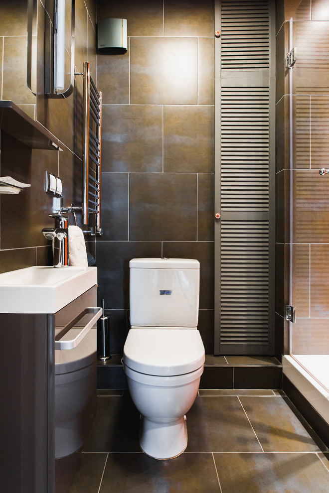 Modern inredning av ett badrum med dusch, med en toalettstol med separat cisternkåpa, brun kakel och ett konsol handfat