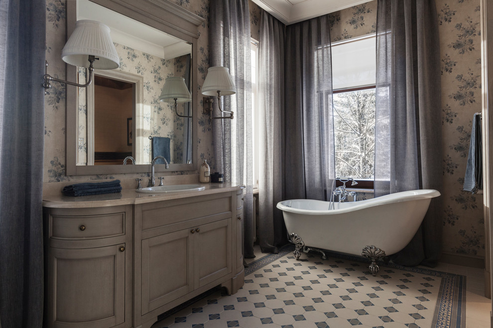 Example of a classic master gray floor claw-foot bathtub design in Moscow with recessed-panel cabinets, gray cabinets, gray walls and a drop-in sink
