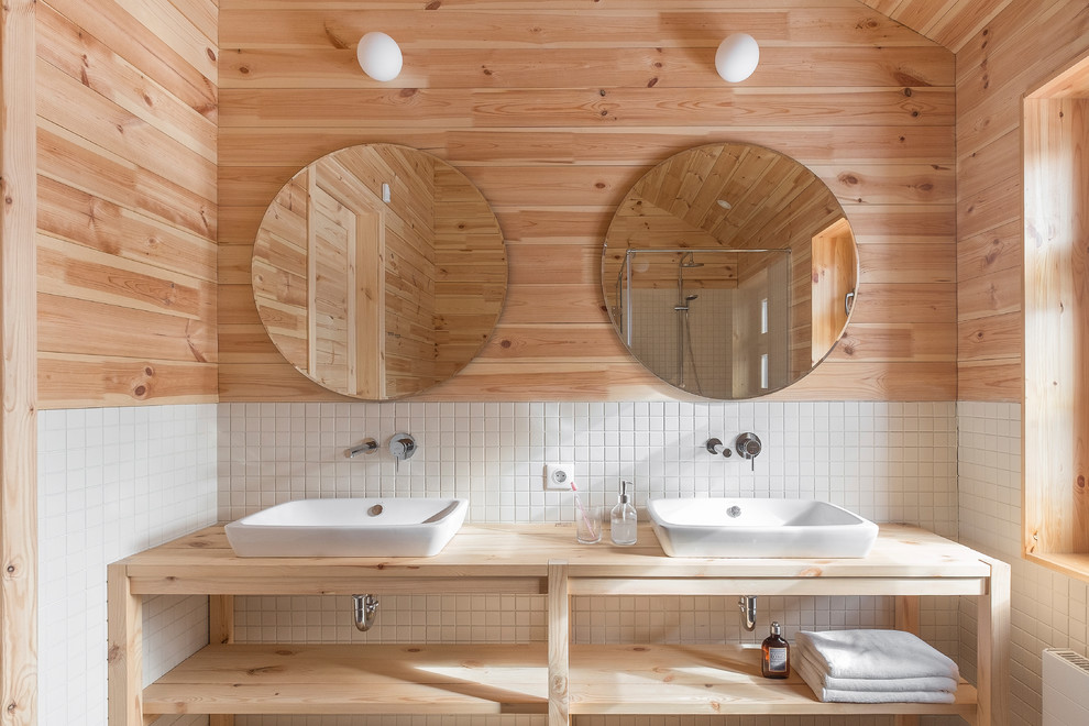 Cette image montre une grande salle de bain rustique en bois clair avec un carrelage blanc, des carreaux de porcelaine, un plan de toilette en bois, un placard sans porte et une vasque.