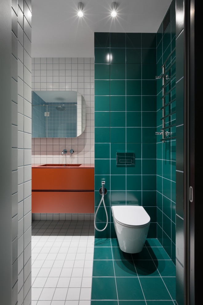 Bild på ett mellanstort funkis orange oranget badrum med dusch, med släta luckor, orange skåp, en vägghängd toalettstol, grön kakel, ett undermonterad handfat, vitt golv, en dusch i en alkov, keramikplattor, klinkergolv i keramik, bänkskiva i akrylsten och dusch med gångjärnsdörr