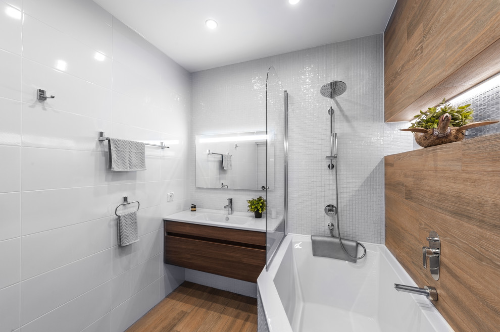 Inspiration för moderna badrum, med en dusch/badkar-kombination, vit kakel, keramikplattor, klinkergolv i porslin, skåp i mellenmörkt trä, ett hörnbadkar, ett integrerad handfat och med dusch som är öppen
