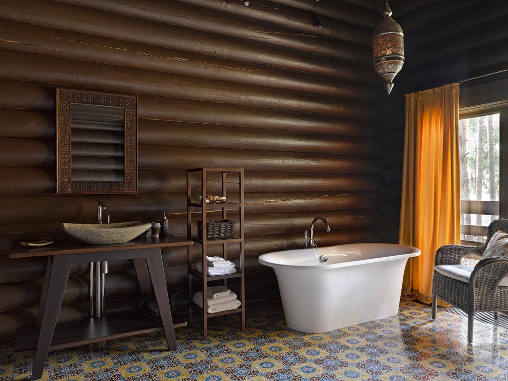 Идея дизайна: главная ванная комната среднего размера, в деревянном доме в стиле рустика с настольной раковиной, темными деревянными фасадами, столешницей из дерева, отдельно стоящей ванной, разноцветной плиткой, коричневыми стенами, разноцветным полом и коричневой столешницей