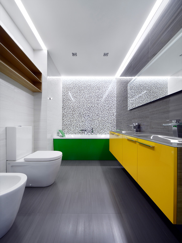 Bild på ett mellanstort funkis badrum för barn, med släta luckor, ett badkar i en alkov, klinkergolv i keramik, bänkskiva i glas, vit kakel, orange skåp, en bidé, keramikplattor, bruna väggar och ett avlångt handfat