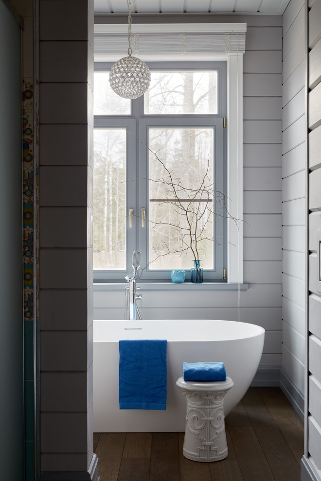 Пример оригинального дизайна: ванная комната в стиле кантри с отдельно стоящей ванной, серыми стенами, темным паркетным полом и коричневым полом