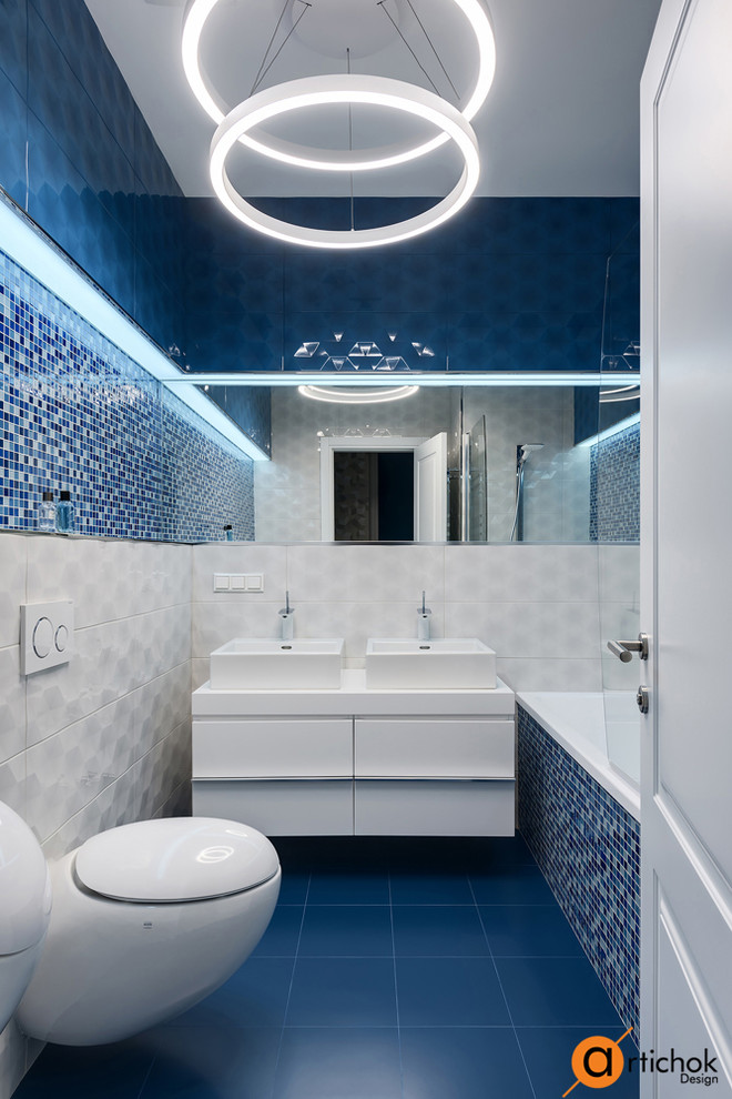 Inspiration för små moderna badrum för barn, med luckor med upphöjd panel, vita skåp, ett badkar i en alkov, en dusch/badkar-kombination, en vägghängd toalettstol, blå kakel, mosaik, blå väggar, klinkergolv i keramik, ett nedsänkt handfat, bänkskiva i akrylsten, blått golv och dusch med duschdraperi