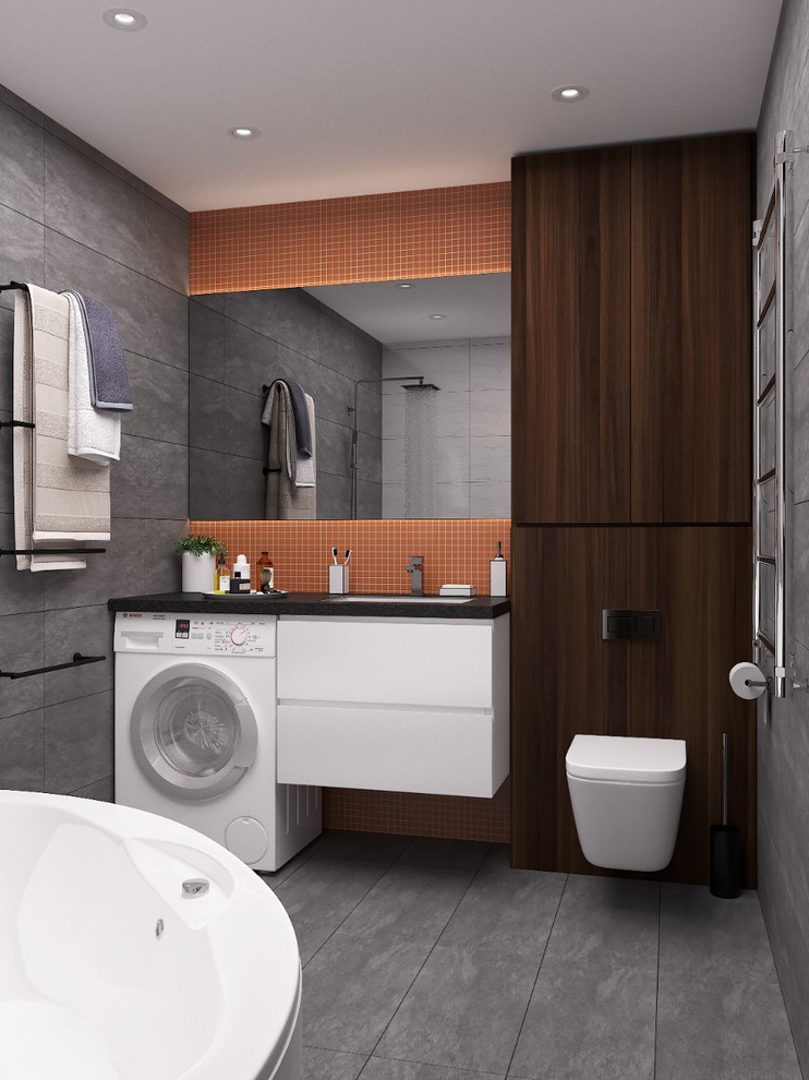 Cette image montre une salle de bain urbaine avec un placard à porte plane, des portes de placard blanches, WC suspendus, un carrelage gris, un mur gris, un lavabo encastré, un sol gris et un plan de toilette marron.