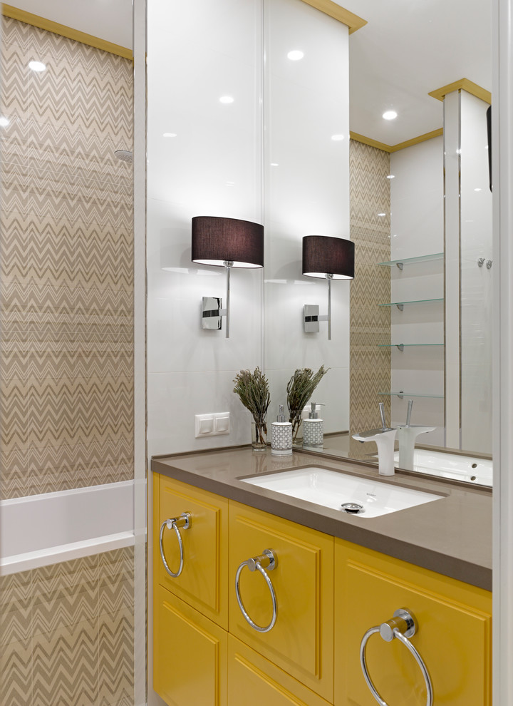 Cette photo montre une salle de bain grise et jaune tendance avec un lavabo encastré, des portes de placard jaunes, un combiné douche/baignoire, un carrelage beige, une baignoire posée et un plan de toilette gris.