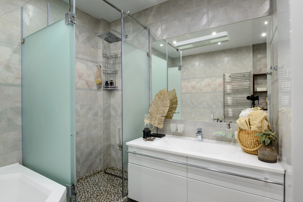 Свежая идея для дизайна: большая главная ванная комната в современном стиле с плоскими фасадами, белыми фасадами, угловой ванной, угловым душем, инсталляцией, серой плиткой, керамической плиткой, серыми стенами, полом из керамической плитки, врезной раковиной, столешницей из искусственного камня, серым полом, душем с распашными дверями и белой столешницей - отличное фото интерьера