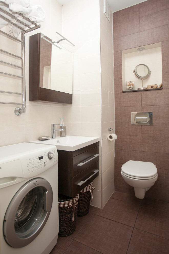 Идея дизайна: ванная комната в скандинавском стиле с плоскими фасадами, коричневыми фасадами, полновстраиваемой ванной, инсталляцией, бежевой плиткой, керамической плиткой, бежевыми стенами, полом из керамической плитки, подвесной раковиной и коричневым полом