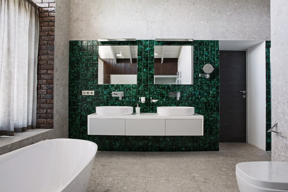 Modern inredning av ett mycket stort en-suite badrum, med grå väggar, ett fristående handfat, släta luckor, grå skåp, ett badkar med tassar, våtrum, ett urinoar, grön kakel, perrakottakakel, klinkergolv i terrakotta, bänkskiva i akrylsten, grått golv och dusch med skjutdörr