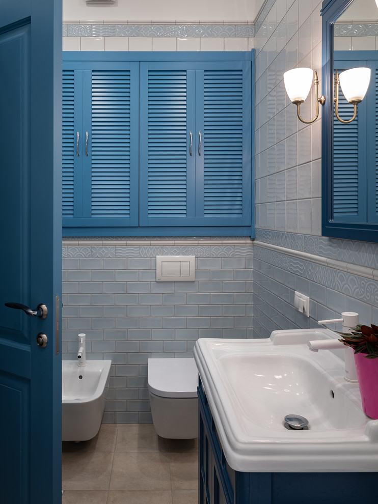 Idee per una piccola stanza da bagno padronale classica con ante con riquadro incassato, ante blu, piastrelle bianche, piastrelle in ceramica, pavimento in gres porcellanato, bidè, lavabo integrato e un lavabo
