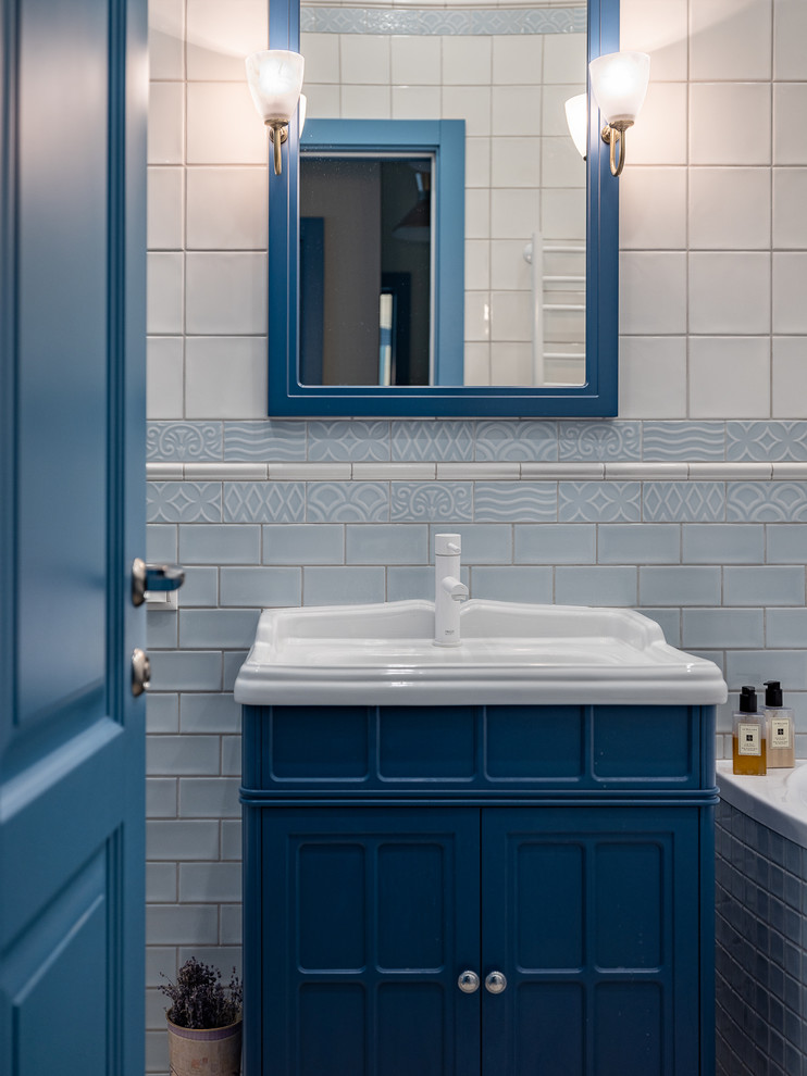 На фото: маленькая главная ванная комната в стиле неоклассика (современная классика) с фасадами с утопленной филенкой, синими фасадами, белой плиткой, керамической плиткой, полом из керамогранита и монолитной раковиной для на участке и в саду