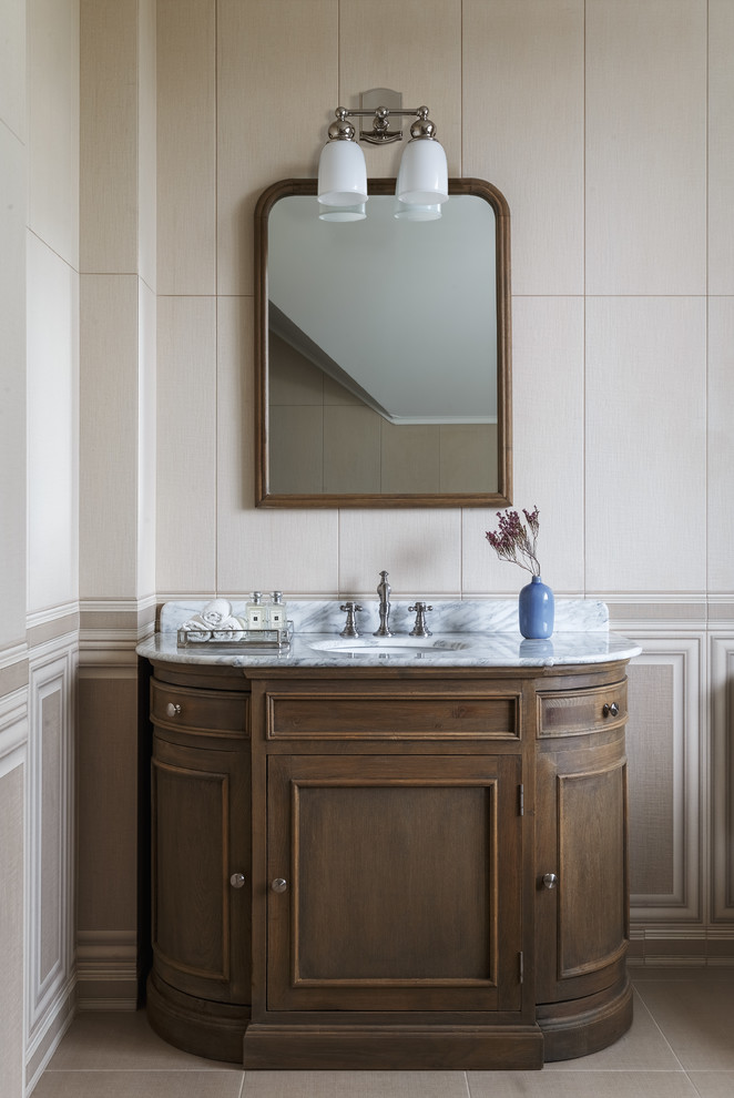 Diseño de cuarto de baño clásico renovado con armarios con paneles empotrados, baldosas y/o azulejos beige, lavabo bajoencimera, encimera de mármol, suelo beige y puertas de armario de madera en tonos medios