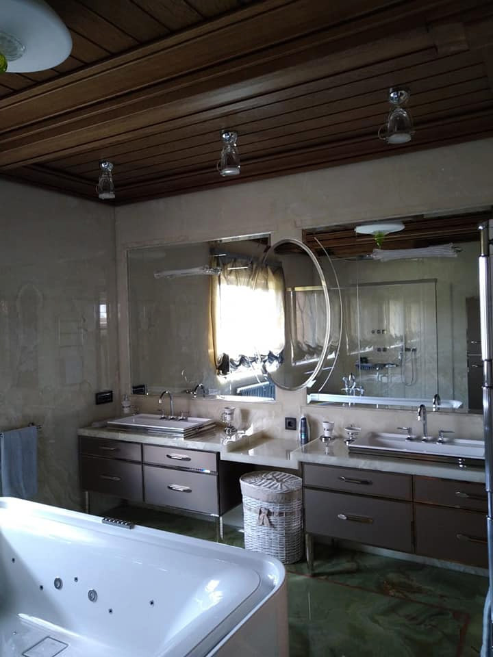 Bild på ett stort vintage grå grått en-suite badrum, med luckor med profilerade fronter, grå skåp, ett fristående badkar, beige kakel, marmorkakel, beige väggar, marmorgolv, ett undermonterad handfat, bänkskiva i onyx och grönt golv