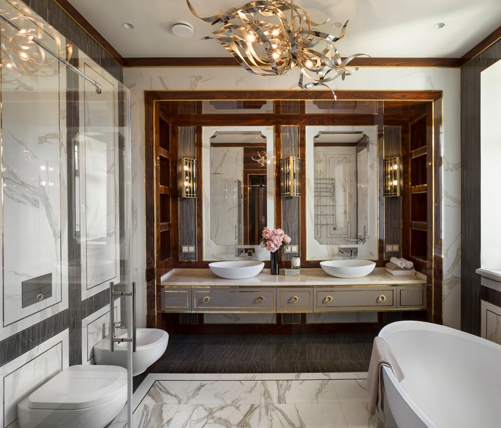 Imagen de cuarto de baño tradicional con armarios con paneles lisos, puertas de armario grises, bañera exenta, bidé, suelo de mármol y lavabo sobreencimera