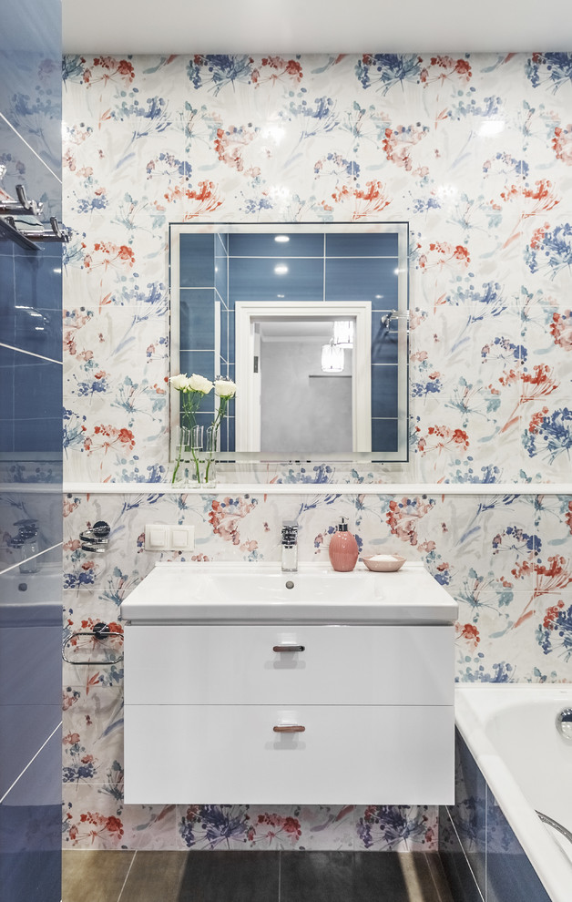 Inspiration for a small contemporary ensuite bathroom in Moscow with flat-panel cabinets, white cabinets, an alcove bath, a shower/bath combination, blue tiles, multi-coloured tiles, a built-in sink and multi-coloured walls.