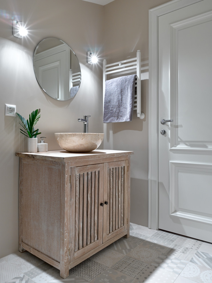 Modelo de cuarto de baño actual con puertas de armario con efecto envejecido, paredes grises, lavabo sobreencimera y encimera de madera