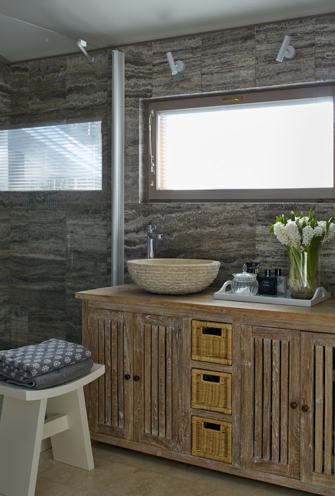 На фото: ванная комната в стиле рустика с искусственно-состаренными фасадами, серой плиткой, душевой кабиной, настольной раковиной и столешницей из дерева с