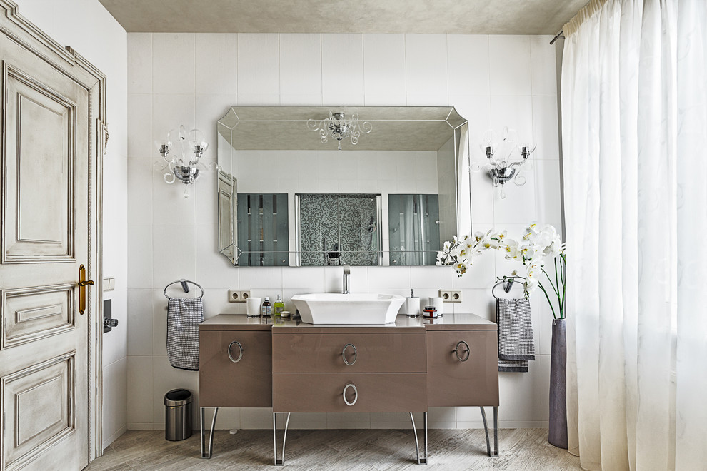 Cette photo montre une salle de bain chic avec une vasque, un carrelage blanc, des portes de placard marrons et un placard à porte plane.