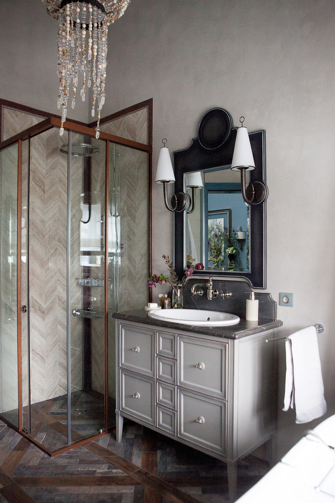 Foto på ett vintage grå badrum med dusch, med luckor med infälld panel, grå skåp, en hörndusch, grå väggar, brunt golv och dusch med skjutdörr