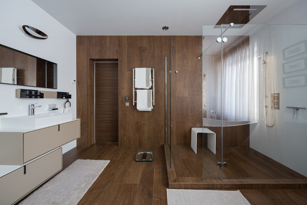 Foto på ett mellanstort funkis en-suite badrum, med släta luckor, en hörndusch, keramikplattor, vita väggar, klinkergolv i porslin, bänkskiva i akrylsten, brunt golv, beige skåp, brun kakel, ett fristående handfat och med dusch som är öppen