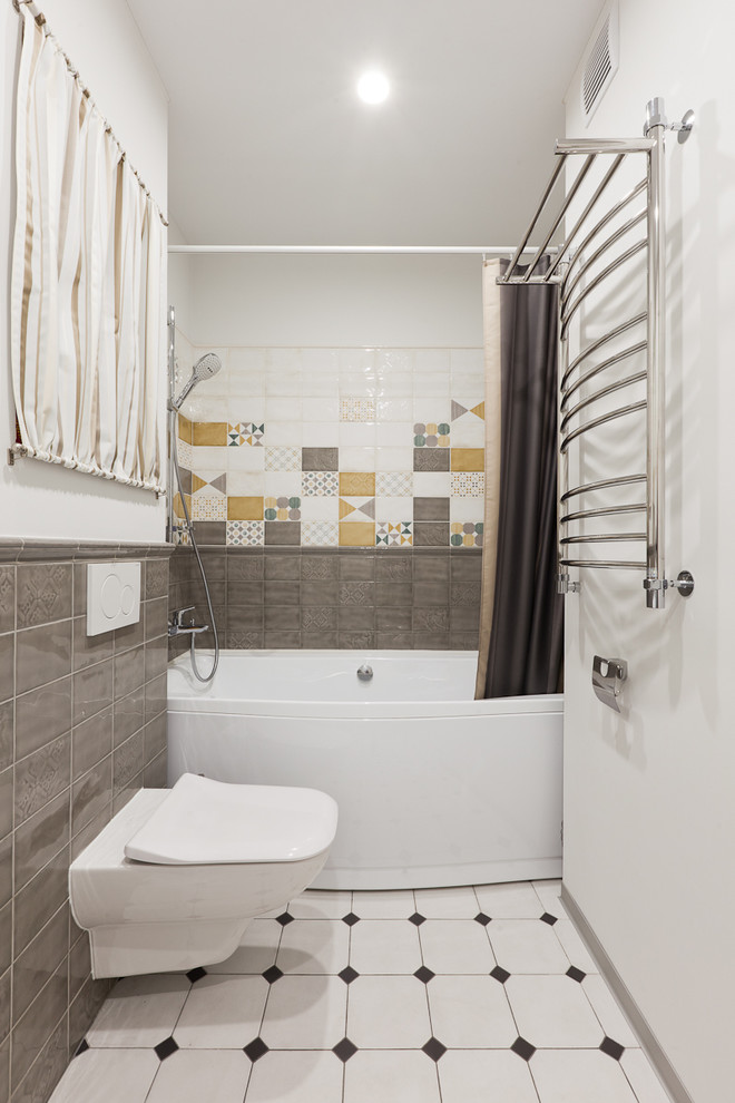 Modelo de cuarto de baño contemporáneo de tamaño medio con combinación de ducha y bañera, sanitario de pared, baldosas y/o azulejos grises, baldosas y/o azulejos de cerámica, paredes blancas, suelo de baldosas de porcelana, bañera empotrada y ducha con cortina