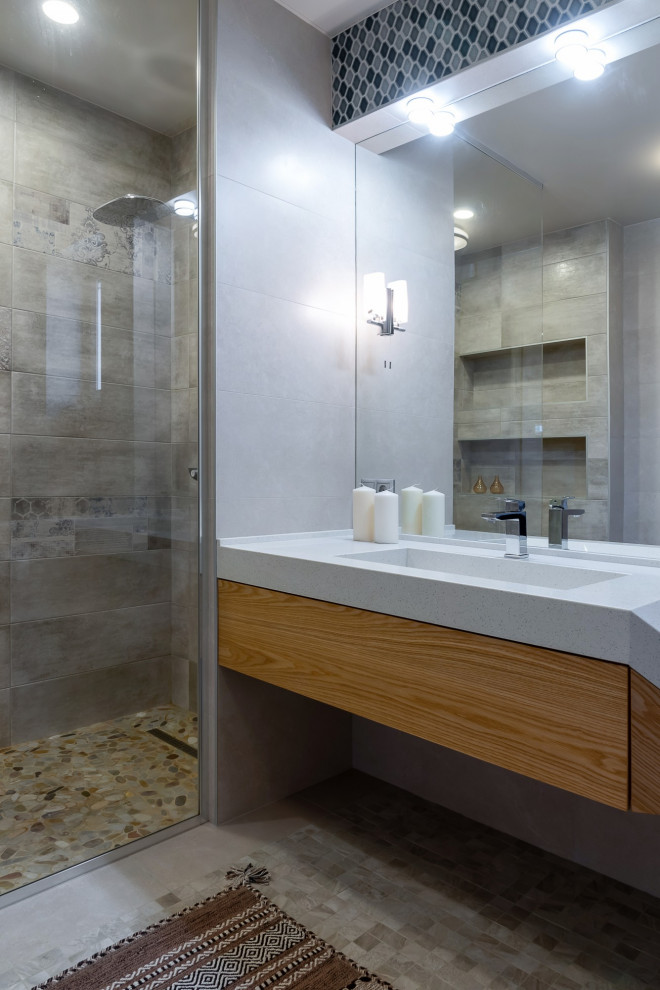 Ispirazione per una stanza da bagno contemporanea con ante lisce, ante in legno chiaro, doccia alcova, piastrelle grigie, pareti grigie, lavabo integrato, pavimento grigio e top bianco