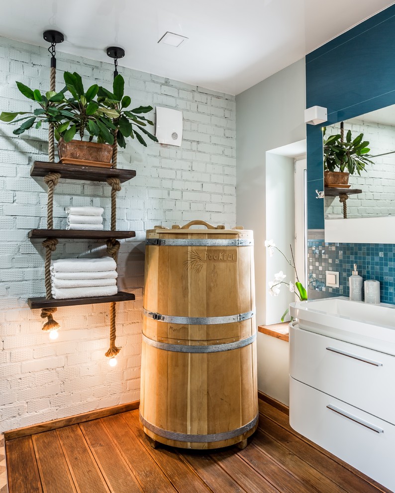 This is an example of a contemporary bathroom in Moscow with flat-panel cabinets, white cabinets, blue tiles, dark hardwood flooring, brown floors, white walls and an integrated sink.