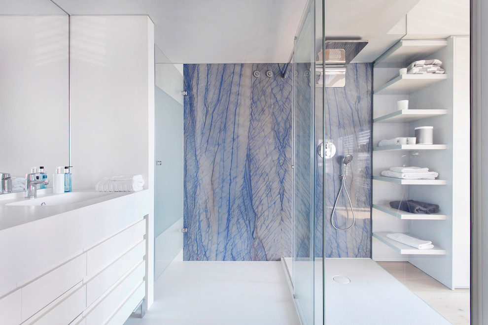 Modelo de cuarto de baño contemporáneo de tamaño medio con ducha abierta, baldosas y/o azulejos azules, paredes azules, aseo y ducha, lavabo integrado y encimera de acrílico