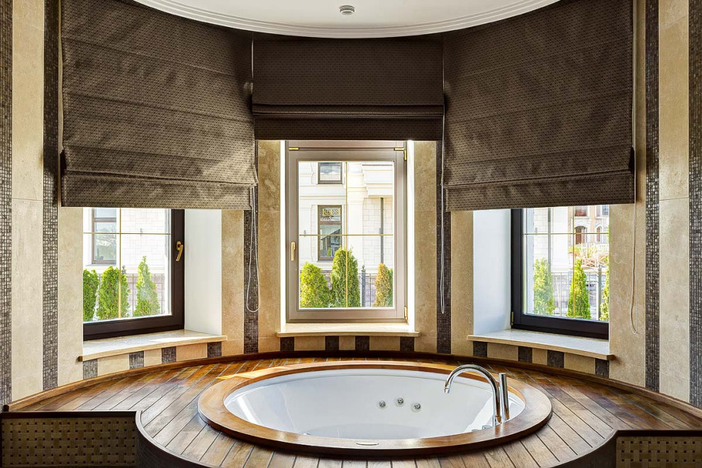 Стильный дизайн: главная ванная комната в современном стиле с полновстраиваемой ванной, бежевой плиткой и коричневым полом - последний тренд