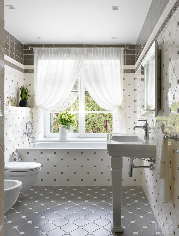 モスクワにあるトランジショナルスタイルのおしゃれな浴室 (アルコーブ型浴槽、壁掛け式トイレ、白いタイル、グレーのタイル、コンソール型シンク、グレーの床) の写真