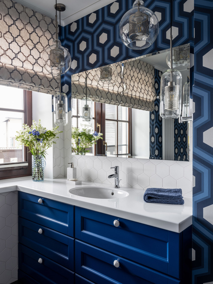 Diseño de cuarto de baño clásico renovado con armarios con paneles empotrados, puertas de armario azules, paredes azules, lavabo bajoencimera, encimeras blancas y baldosas y/o azulejos blancos
