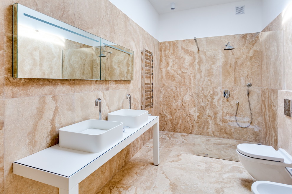 Diseño de cuarto de baño actual grande con sanitario de pared, aseo y ducha, armarios abiertos, puertas de armario blancas, ducha a ras de suelo, baldosas y/o azulejos beige y lavabo sobreencimera