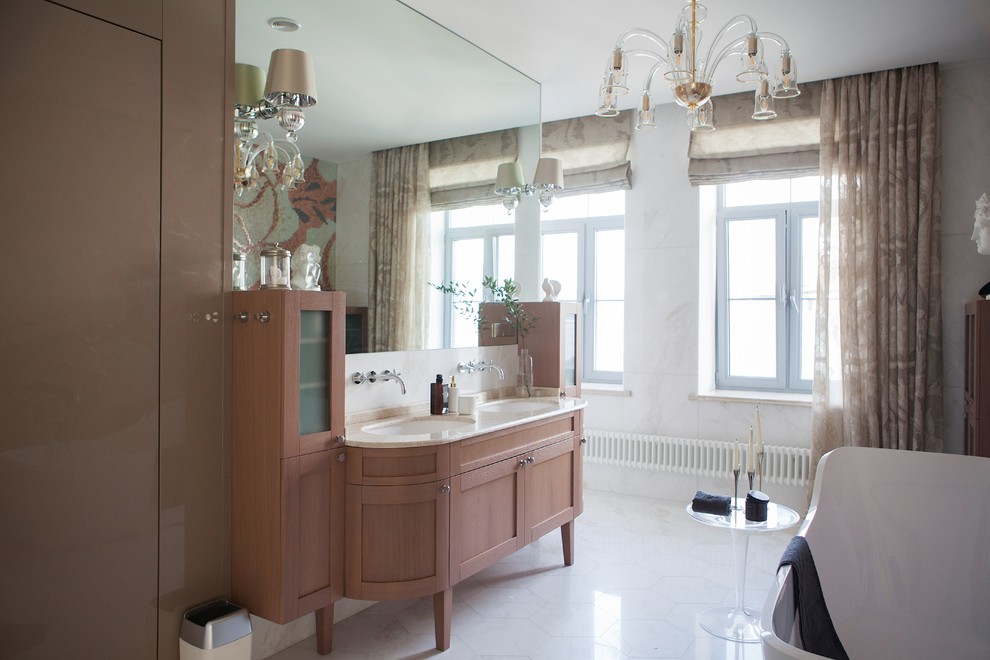 Стильный дизайн: главная ванная комната в классическом стиле с фасадами с утопленной филенкой, фасадами цвета дерева среднего тона, отдельно стоящей ванной, белой плиткой, белыми стенами, врезной раковиной, белым полом и бежевой столешницей - последний тренд