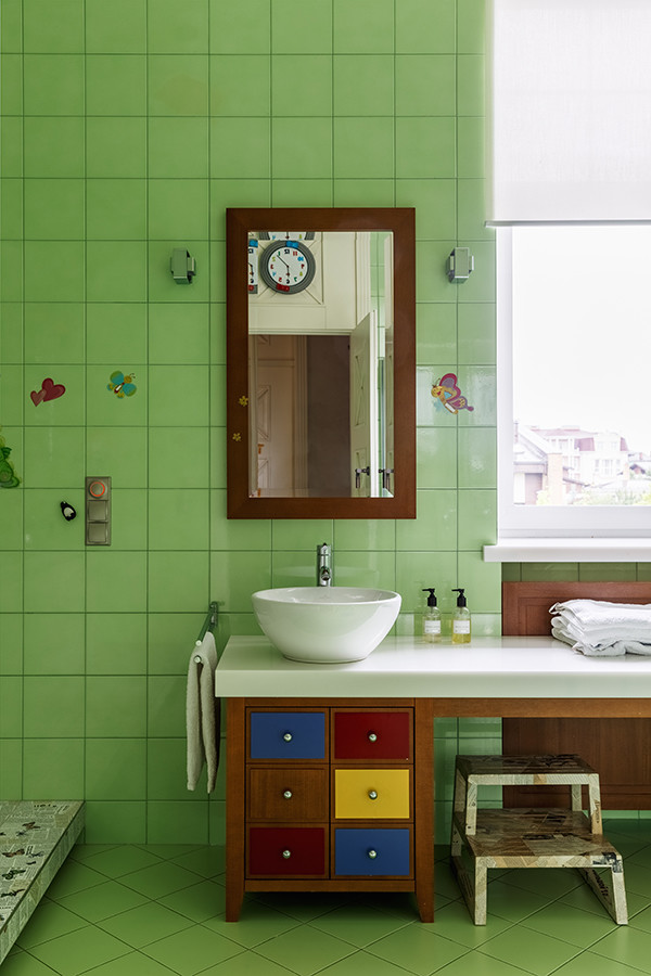 Aménagement d'une salle de bain contemporaine pour enfant avec un placard à porte plane, des portes de placard noires, un carrelage vert, une vasque et un sol vert.