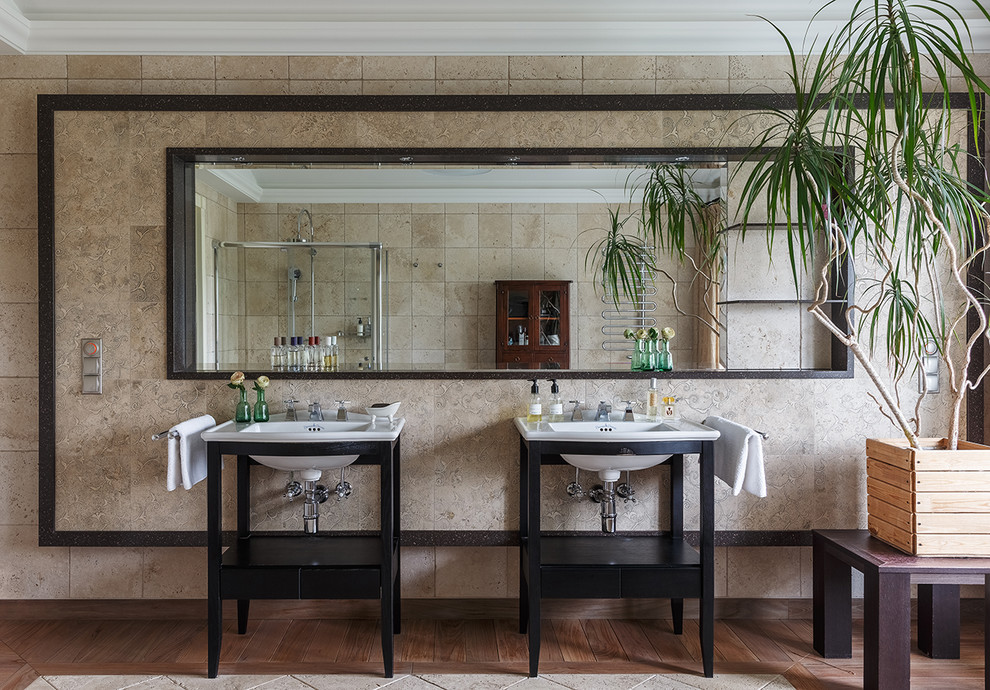 На фото: ванная комната в стиле неоклассика (современная классика) с черными фасадами, бежевой плиткой, коричневым полом и консольной раковиной с