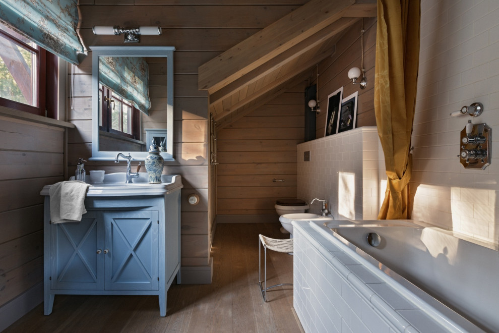 На фото: главная ванная комната в стиле рустика с фасадами с утопленной филенкой, синими фасадами, накладной ванной, серой плиткой, плиткой кабанчик, тумбой под одну раковину, напольной тумбой, деревянными стенами, деревянным потолком и светлым паркетным полом с