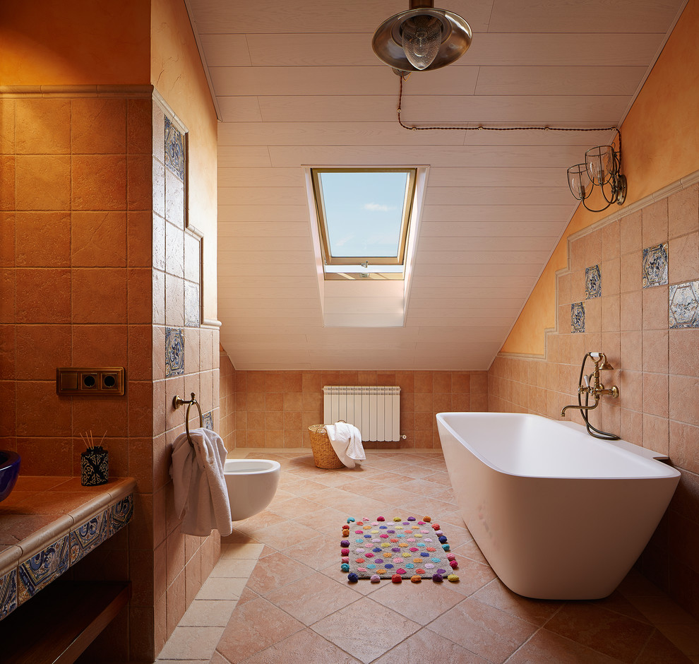 Immagine di una piccola stanza da bagno per bambini mediterranea con vasca freestanding, WC sospeso, piastrelle beige, piastrelle in pietra, pareti beige, pavimento in terracotta e top alla veneziana