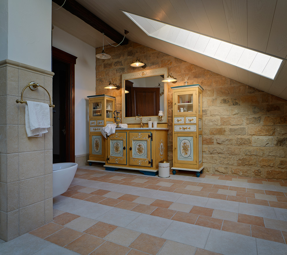 Foto på ett mellanstort medelhavsstil badrum, med skåp i ljust trä, beige kakel, stenkakel, bruna väggar, klinkergolv i terrakotta, träbänkskiva och luckor med infälld panel