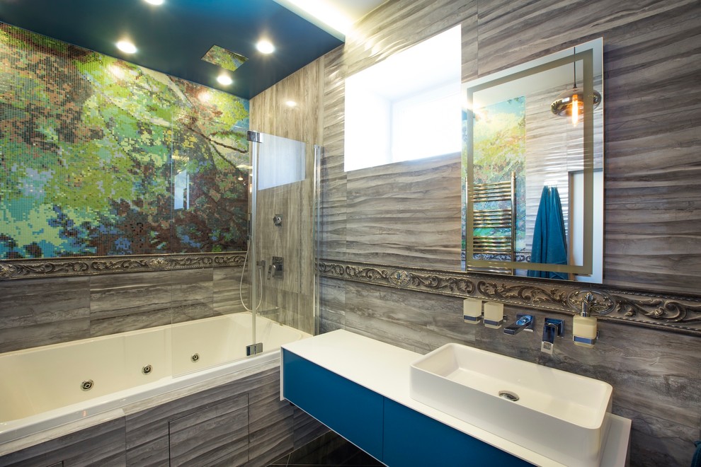 Immagine di una grande stanza da bagno padronale industriale con ante lisce, ante blu, vasca ad alcova, vasca/doccia, piastrelle grigie e lavabo a bacinella