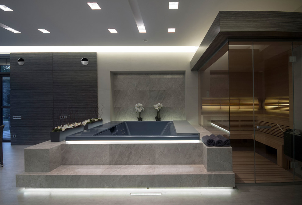 Cette photo montre un sauna tendance avec un bain bouillonnant et un mur gris.