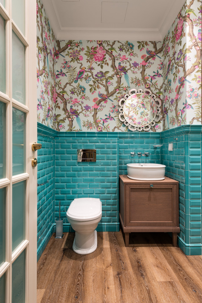 Mid-sized trendy blue tile and porcelain tile medium tone wood floor and brown floor powder room photo in Moscow with recessed-panel cabinets, brown cabinets, a wall-mount toilet, a vessel sink, wood countertops and brown countertops