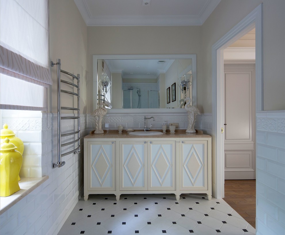 Пример оригинального дизайна: ванная комната среднего размера в классическом стиле с фасадами с выступающей филенкой, белой плиткой, плиткой кабанчик, бежевыми стенами, накладной раковиной, белым полом и бежевой столешницей