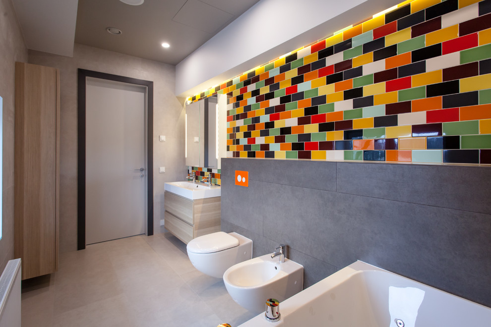 На фото: детская ванная комната среднего размера в современном стиле с накладной ванной, душем над ванной, инсталляцией, разноцветной плиткой, керамической плиткой, разноцветными стенами, полом из керамогранита, раковиной с несколькими смесителями и бежевым полом