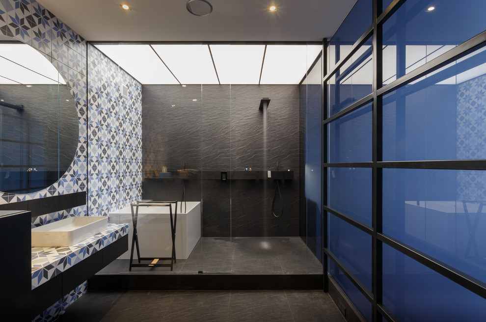 На фото: главная ванная комната в современном стиле с угловой ванной, душевой комнатой, разноцветной плиткой, настольной раковиной и черным полом