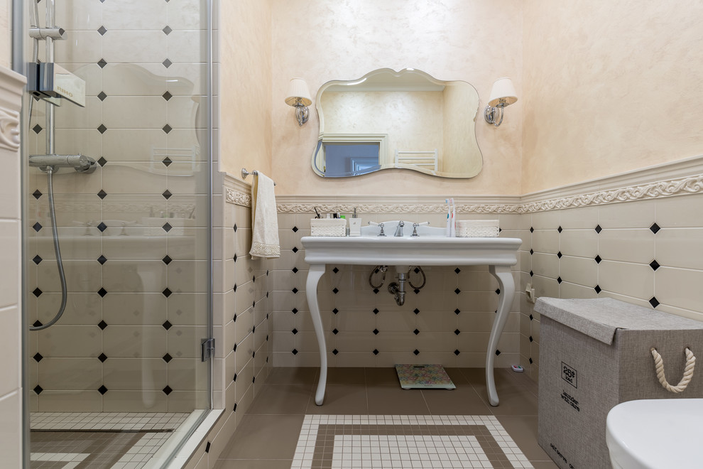 Modelo de cuarto de baño clásico renovado con ducha empotrada, paredes beige, aseo y ducha, lavabo tipo consola, suelo marrón y baldosas y/o azulejos grises